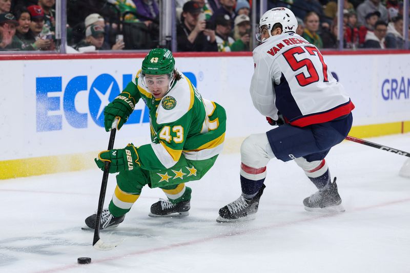 Dec 16, 2025; Saint Paul, Minnesota, USA; Minnesota Wild defenseman Quinn Hughes (43) controls the puck as Washington Capitals defenseman Trevor van Riemsdyk (57) defends during the first period at Grand Casino Arena. Mandatory Credit: Matt Krohn-Imagn Images