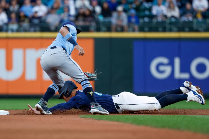 Aug 27, 2024; Seattle, Washington, USA; Tampa Bay Rays shortstop Jose Caballero (7) tags out Seattle Mariners third baseman Dylan Moore (25) on a stolen base attempt during the third inning at T-Mobile Park. Mandatory Credit: Joe Nicholson-USA TODAY Sports