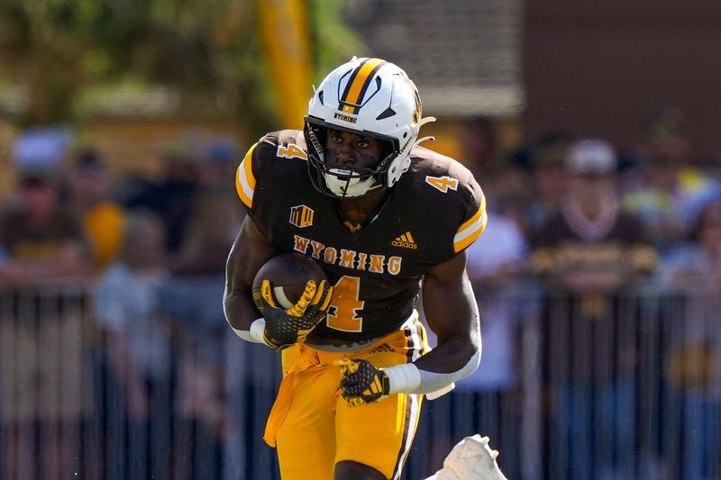 Sep 30, 2023; Laramie, Wyoming, USA; Wyoming Cowboys running back Harrison Waylee (4) runs against the New Mexico Lobos during the first quarter at Jonah Field at War Memorial Stadium. Mandatory Credit: Troy Babbitt-USA TODAY Sports

