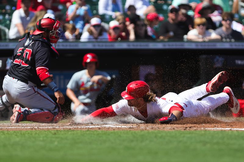 Mar 11, 2024; Jupiter, Florida, USA; St. Louis Cardinals second baseman Brendan Donovan (33) slides at home plate and scores against the Washington Nationals during the fourth inning at Roger Dean Chevrolet Stadium. Mandatory Credit: Sam Navarro-USA TODAY Sports