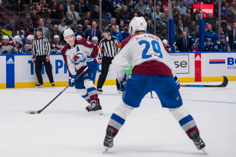 Mar 13, 2024; Vancouver, British Columbia, CAN; Colorado Avalanche defenseman Cale Makar (8) passes the puck to forward Nathan MacKinnon (29) in overtime against the Vancouver Canucks at Rogers Arena. Colorado won 4 -3 in overtime. Mandatory Credit: Bob Frid-USA TODAY Sports