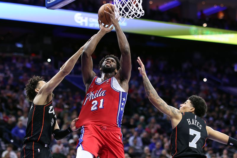 PHILADELPHIA, PENNSYLVANIA - DECEMBER 15: Joel Embiid #21 of the Philadelphia 76ers attempts a lay up between Cade Cunningham #2 and Killian Hayes #7 of the Detroit Pistons during the third quarter at the Wells Fargo Center on December 15, 2023 in Philadelphia, Pennsylvania. NOTE TO USER: User expressly acknowledges and agrees that, by downloading and or using this photograph, User is consenting to the terms and conditions of the Getty Images License Agreement. (Photo by Tim Nwachukwu/Getty Images)