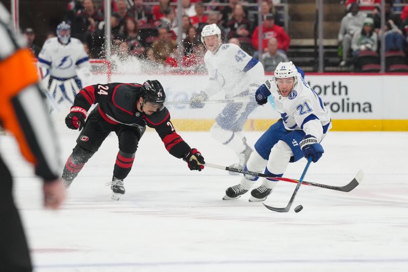 Feb 26, 2026; Raleigh, North Carolina, USA;  Tampa Bay Lightning center Brayden Point (21) and Carolina Hurricanes center Seth Jarvis (24) skate after the puck during the second period at Lenovo Center. Mandatory Credit: James Guillory-Imagn Images