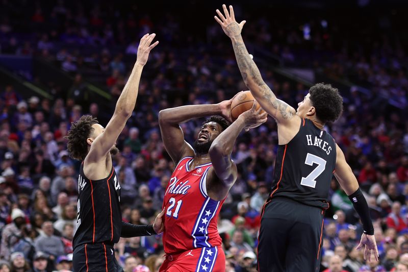 PHILADELPHIA, PENNSYLVANIA - DECEMBER 15: Joel Embiid #21 of the Philadelphia 76ers attempts a lay up between Cade Cunningham #2 and Killian Hayes #7 of the Detroit Pistons during the third quarter at the Wells Fargo Center on December 15, 2023 in Philadelphia, Pennsylvania. NOTE TO USER: User expressly acknowledges and agrees that, by downloading and or using this photograph, User is consenting to the terms and conditions of the Getty Images License Agreement. (Photo by Tim Nwachukwu/Getty Images)