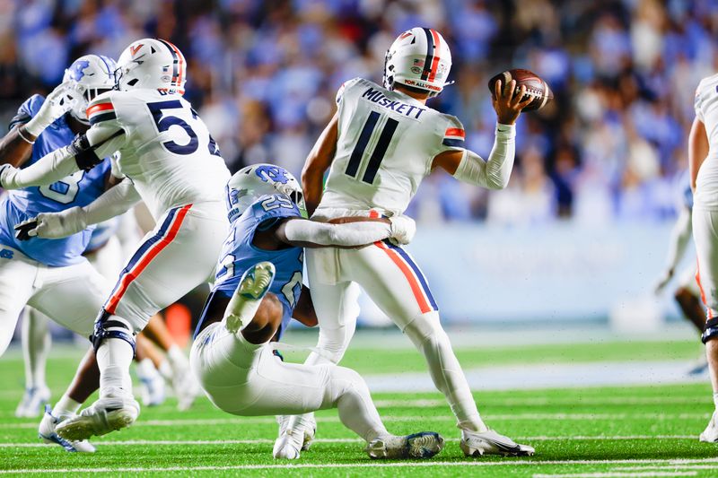 Oct 21, 2023; Chapel Hill, North Carolina, USA; Virginia Cavaliers quarterback Tony Muskett (11) tries to get rid of the football as he is brought down by North Carolina Tar Heels linebacker Kaimon Rucker (25) in the first half at Kenan Memorial Stadium. Mandatory Credit: Nell Redmond-USA TODAY Sports