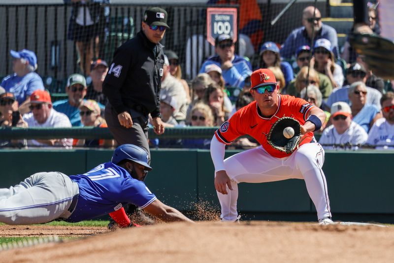 Feb 25, 2026; Lakeland, Florida, USA; Toronto Blue Jays first baseman Vladimir Guerrero Jr. (27) slides to first infant of Detroit Tigers first baseman Spencer Torkelson (20) at Publix Field at Joker Marchant Stadium. Mandatory Credit: Mike Watters-Imagn Images