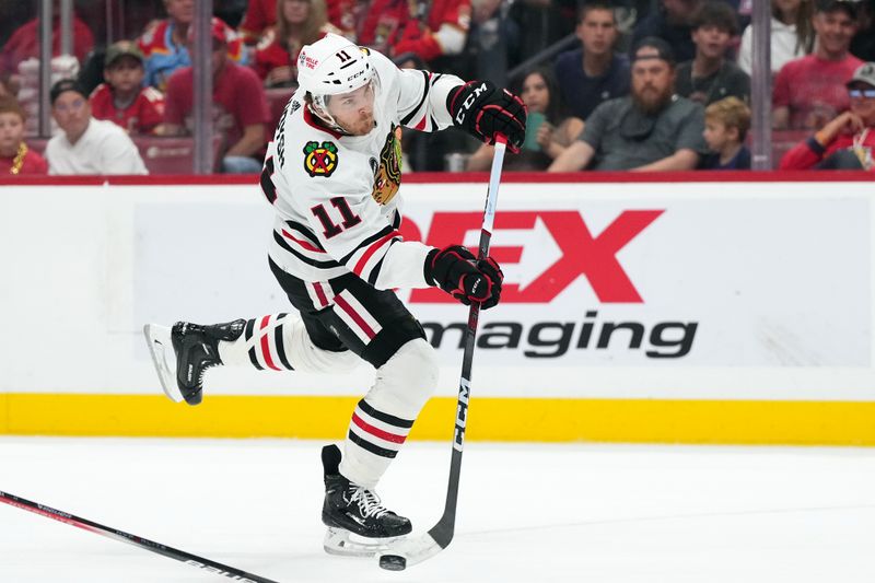 Nov 12, 2023; Sunrise, Florida, USA; Chicago Blackhawks right wing Taylor Raddysh (11) shoots the puck against the Florida Panthers during the first period at Amerant Bank Arena. Mandatory Credit: Jasen Vinlove-USA TODAY Sports