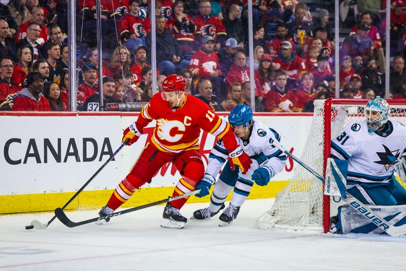 Apr 18, 2024; Calgary, Alberta, CAN; Calgary Flames center Mikael Backlund (11) and San Jose Sharks defenseman Henry Thrun (3) battles for the puck during the second period at Scotiabank Saddledome. Mandatory Credit: Sergei Belski-USA TODAY Sports