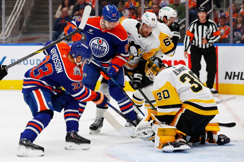 Oct 25, 2024; Edmonton, Alberta, CAN; Edmonton Oilers forward Victor Arvidsson (33) jams at a loose puck in front of Pittsburgh Penguins goaltender Joel Blomqvist (30) during the first period at Rogers Place. Mandatory Credit: Perry Nelson-Imagn Images