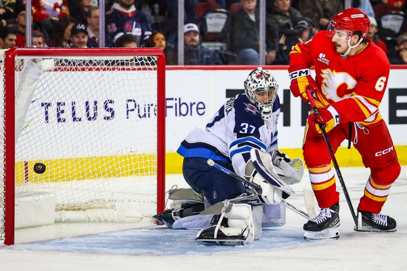 Nov 15, 2025; Calgary, Alberta, CAN; Calgary Flames center Rory Kerins (6) screens in front of Winnipeg Jets goaltender Connor Hellebuyck (37) as the puck hits the post during the second period at Scotiabank Saddledome. Mandatory Credit: Sergei Belski-Imagn Images