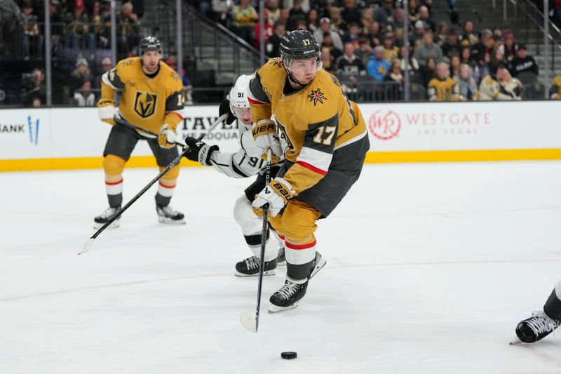 Dec 28, 2023; Las Vegas, Nevada, USA; Vegas Golden Knights defenseman Ben Hutton (17) skates with the puck against Los Angeles Kings right wing Carl Grundstrom (91) during the first period at T-Mobile Arena. Mandatory Credit: Lucas Peltier-USA TODAY Sports