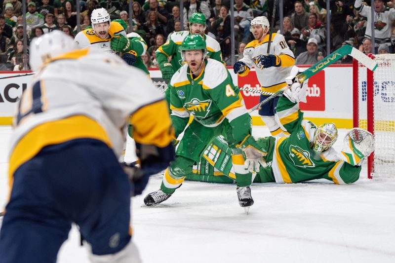 Dec 31, 2024; Saint Paul, Minnesota, USA; Minnesota Wild goaltender Filip Gustavsson (32) is upended in goal as Nashville Predators center Gustav Nyquist (14) takes a shot in the third period at Xcel Energy Center. Mandatory Credit: Matt Blewett-Imagn Images