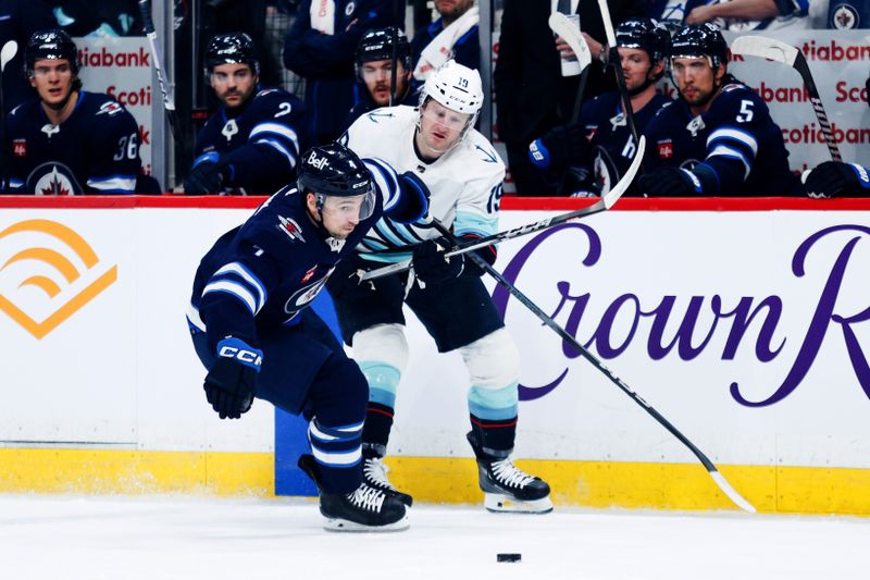 Apr 16, 2024; Winnipeg, Manitoba, CAN;  Winnipeg Jets defenseman Neal Pionk (4) and Seattle Kraken forward Jared McCann (19) battle for the puck during the first period at Canada Life Centre. Mandatory Credit: Terrence Lee-USA TODAY Sports