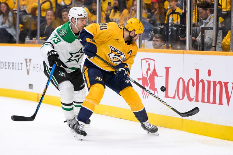 Oct 10, 2024; Nashville, Tennessee, USA;  Nashville Predators center Ryan O'Reilly (90) and Dallas Stars defenseman Esa Lindell (23) fight for the puck during the first period at Bridgestone Arena. Mandatory Credit: Steve Roberts-Imagn Images