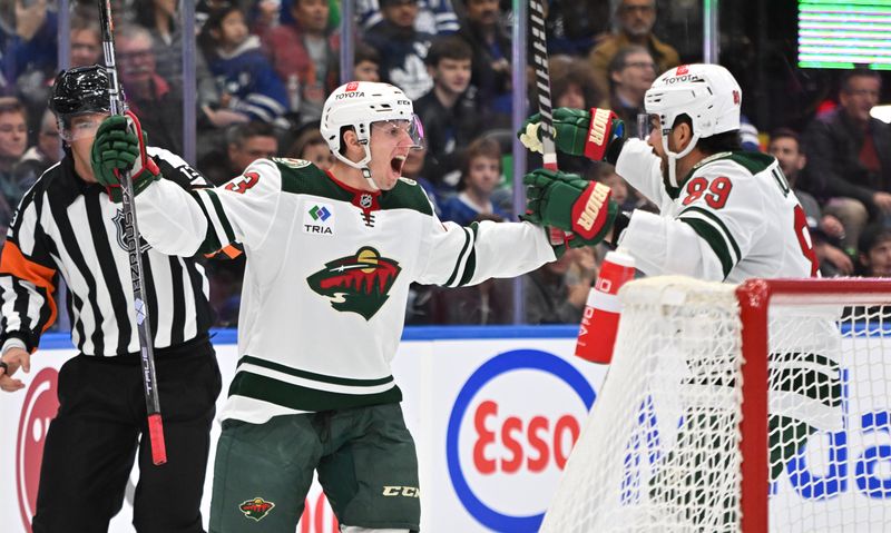 Oct 14, 2023; Toronto, Ontario, CAN;   Minnesota Wild forward Marco Rossi (23) celebrates with forward Frederick Gaudreau (89) after scoring against the Toronto Maple Leafs in the second period at Scotiabank Arena. Mandatory Credit: Dan Hamilton-USA TODAY Sports