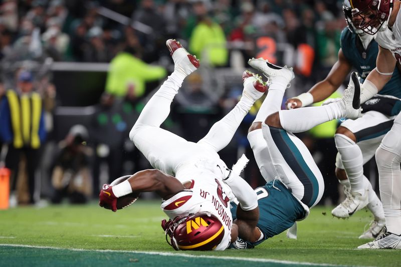 Washington Commanders running back Brian Robinson Jr. (8) reaches for the end zone with the ball as Philadelphia Eagles safety C.J. Gardner-Johnson (8) defends during an NFL football game, Thursday, Nov. 14, 2024, in Philadelphia, PA. (AP Photo/Peter Joneleit)