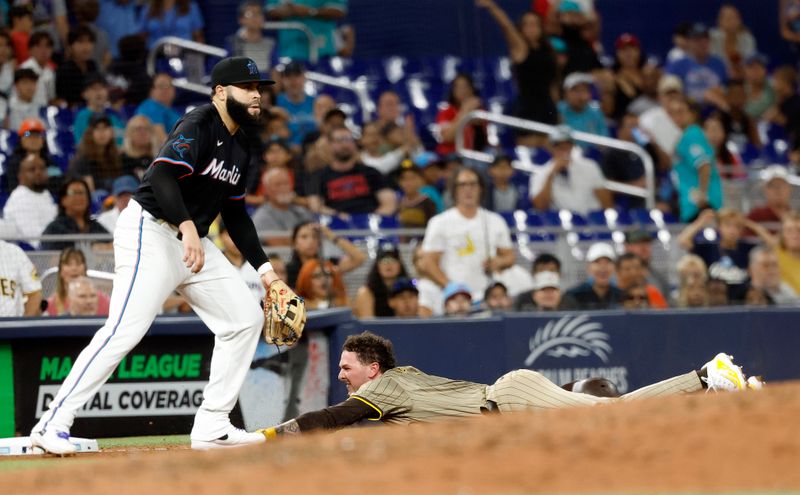 Aug 9, 2024; Miami, Florida, USA;  San Diego Padres center fielder Jackson Merrill (3) slides safely into third base in front of Miami Marlins third baseman Emmanuel Rivera (15) the in the seventh inning at loanDepot Park. Mandatory Credit: Rhona Wise-USA TODAY Sports