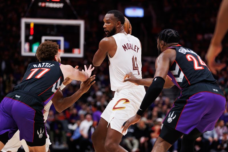 TORONTO, CANADA - OCTOBER 23: Evan Mobley #4 of the Cleveland Cavaliers looks to pass against Jamison Battle #77 and Bruno Fernando #24 of the Toronto Raptors during the second half  at Scotiabank Arena on October 23, 2024 in Toronto, Ontario, Canada. NOTE TO USER: User expressly acknowledges and agrees that, by downloading and or using this photograph, User is consenting to the terms and conditions of the Getty Images License Agreement. (Photo by Cole Burston/Getty Images)