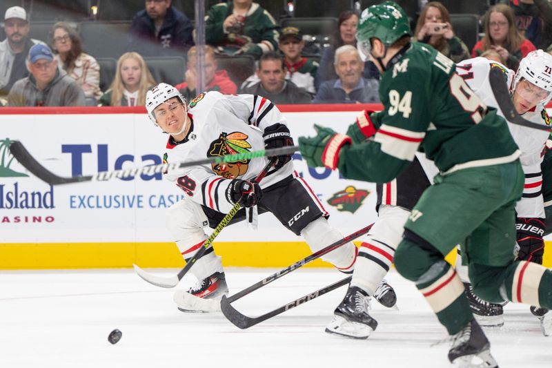 Oct 1, 2024; Saint Paul, Minnesota, USA; Chicago Blackhawks center Connor Bedard (98) passes as Minnesota Wild forward Jake Lauko (94) defends in the third period at Xcel Energy Center. Mandatory Credit: Matt Blewett-Imagn Images