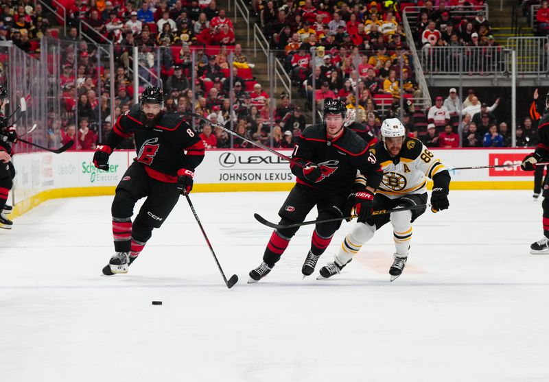 Oct 31, 2024; Raleigh, North Carolina, USA;  Carolina Hurricanes defenseman Brent Burns (8) and right wing Andrei Svechnikov (37) skate after the puck against Boston Bruins right wing David Pastrnak (88) during the first period at Lenovo Center. Mandatory Credit: James Guillory-Imagn Images