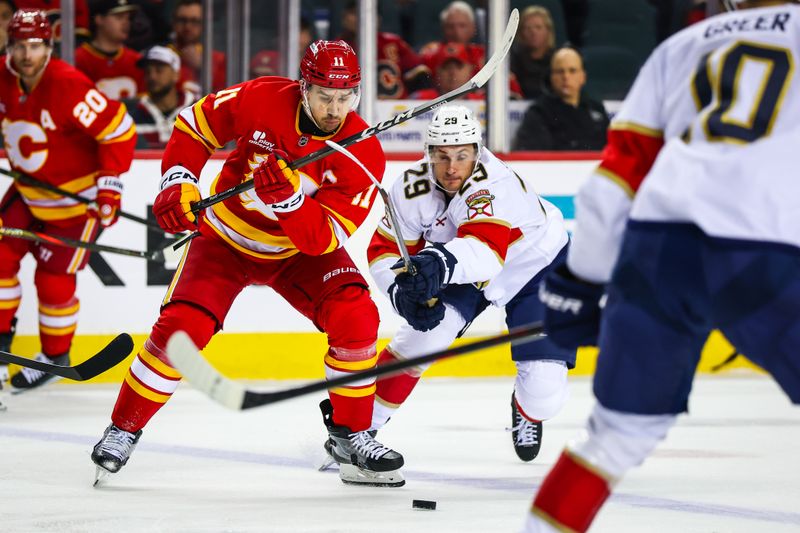 Mar 20, 2026; Calgary, Alberta, CAN; Calgary Flames center Mikael Backlund (11) and Florida Panthers left wing Cole Reinhardt (29) battle for the puck during the second period at Scotiabank Saddledome. Mandatory Credit: Sergei Belski-Imagn Images