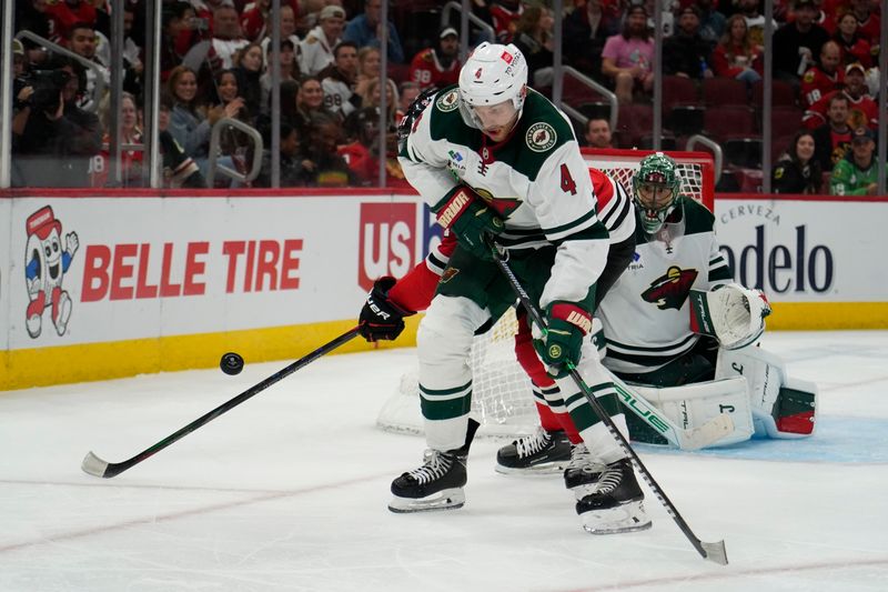 Oct 4, 2024; Chicago, Illinois, USA; Minnesota Wild defenseman Jon Merrill (4) defends against the Chicago Blackhawks during the third period at United Center. Mandatory Credit: David Banks-Imagn Images