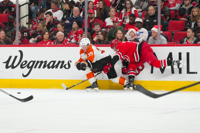 Dec 14, 2025; Raleigh, North Carolina, USA;  Philadelphia Flyers right wing Matvei Michkov (39) and Carolina Hurricanes defenseman Sean Walker (26) battle for the puck during the second period at Lenovo Center. Mandatory Credit: James Guillory-Imagn Images