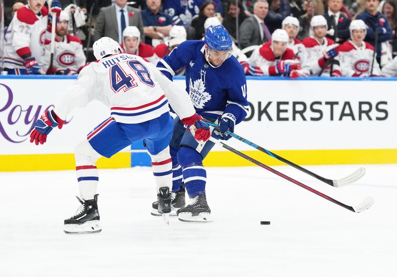 Nov 9, 2024; Toronto, Ontario, CAN; Toronto Maple Leafs center Max Domi (11) battles for the puck with Montreal Canadiens defenseman Lane Hutson (48) during the third period at Scotiabank Arena. Mandatory Credit: Nick Turchiaro-Imagn Images