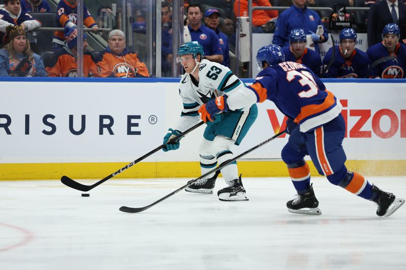 Jan 18, 2025; Elmont, New York, USA; San Jose Sharks center Ty Dellandrea (53) moves the puck defended by New York Islanders defenseman Isaiah George (36) during the first period at UBS Arena. Mandatory Credit: Thomas Salus-Imagn Images