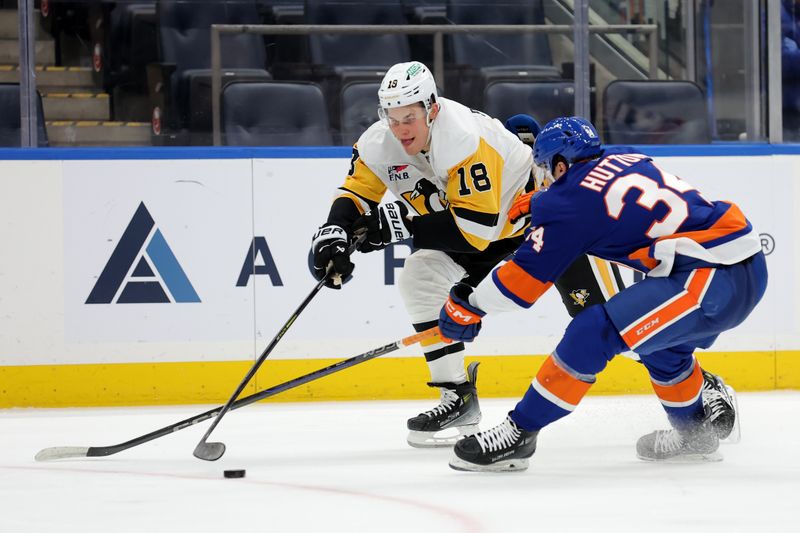 Nov 5, 2024; Elmont, New York, USA; Pittsburgh Penguins right wing Jesse Puljujarvi (18) plays the puck against New York Islanders defenseman Grant Hutton (34) during the third period at UBS Arena. Mandatory Credit: Brad Penner-Imagn Images