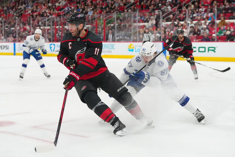 Feb 26, 2026; Raleigh, North Carolina, USA;  Carolina Hurricanes center Jordan Staal (11) skates with the puck past Tampa Bay Lightning defenseman Declan Carlile (67) during the first period at Lenovo Center. Mandatory Credit: James Guillory-Imagn Images
