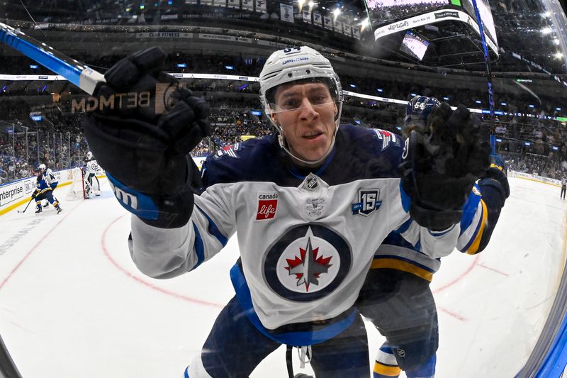 Dec 17, 2025; St. Louis, Missouri, USA; Winnipeg Jets defenseman Logan Stanley (64) slams in to the glass after missing a check on St. Louis Blues right wing Dalibor Dvorsky (54) during the second period at Enterprise Center. Mandatory Credit: Jeff Curry-Imagn Images