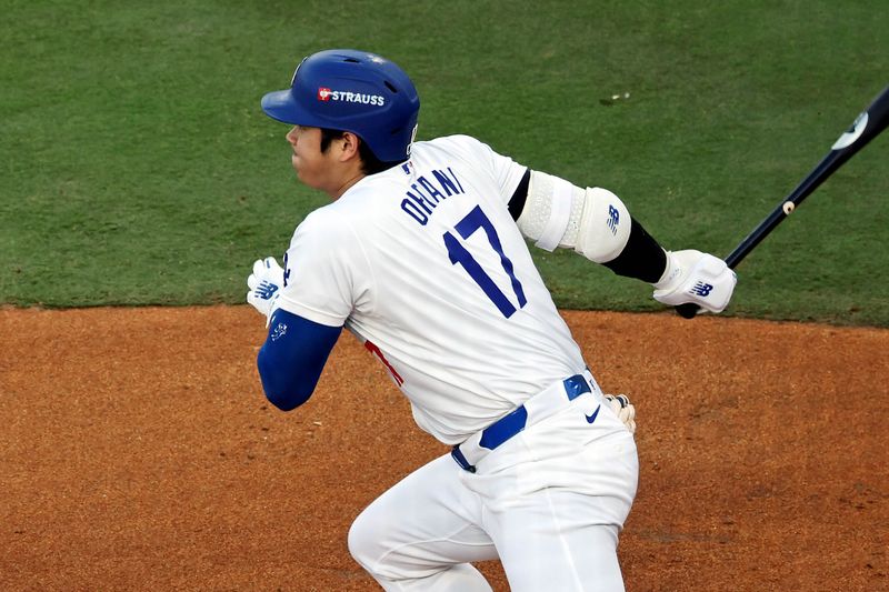 Oct 20, 2024; Los Angeles, California, USA; Los Angeles Dodgers two-way player Shohei Ohtani (17) hits a single during the first inning against the New York Mets during game six of the NLCS for the 2024 MLB playoffs at Dodger Stadium. Mandatory Credit: Kiyoshi Mio-Imagn Images