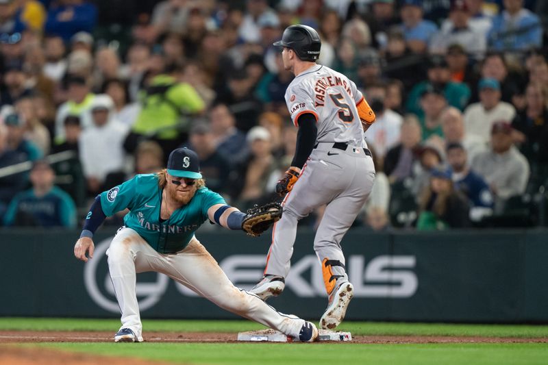 Aug 23, 2024; Seattle, Washington, USA; San Francisco Giants right fielder Mike Yastrzemski (5) beats out a throw to Seattle Mariners first baseman Justin Turner (2) during the third inning at T-Mobile Park. Mandatory Credit: Stephen Brashear-USA TODAY Sports