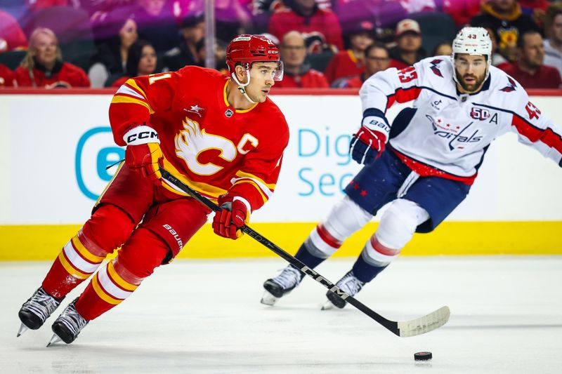 Jan 28, 2025; Calgary, Alberta, CAN; Calgary Flames center Mikael Backlund (11) skates with the puck against Washington Capitals right wing Tom Wilson (43) during the first period at Scotiabank Saddledome. Mandatory Credit: Sergei Belski-Imagn Images