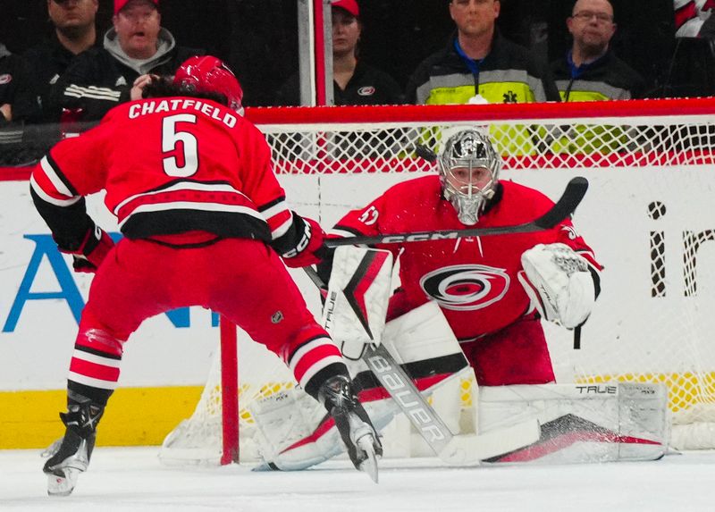 Nov 26, 2023; Raleigh, North Carolina, USA; Carolina Hurricanes goaltender Pyotr Kochetkov (52) and defenseman Jalen Chatfield (5) watch the puck against the Columbus Blue Jackets during the first period at PNC Arena. Mandatory Credit: James Guillory-USA TODAY Sports