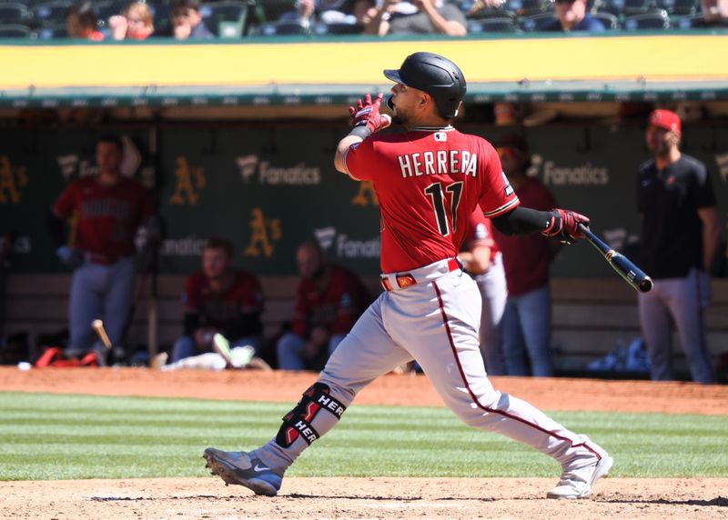 May 17, 2023; Oakland, California, USA; Arizona Diamondbacks catcher Jose Herrera (11) hits a sacrifice fly to send in an RBI against the Oakland Athletics during the ninth inning at Oakland-Alameda County Coliseum. Mandatory Credit: Kelley L Cox-USA TODAY Sports