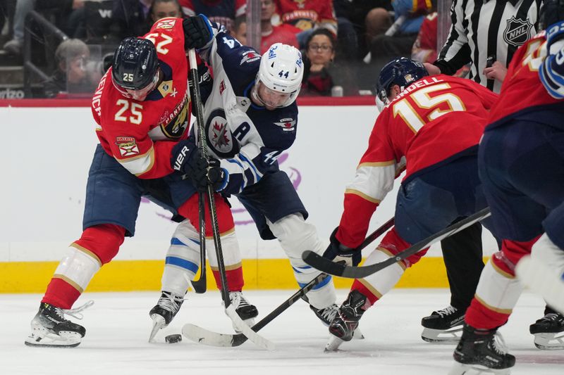 Nov 16, 2024; Sunrise, Florida, USA;  Florida Panthers right wing Mackie Samoskevich (25) and Winnipeg Jets defenseman Josh Morrissey (44) battle for possession during the second period at Amerant Bank Arena. Mandatory Credit: Jim Rassol-Imagn Images