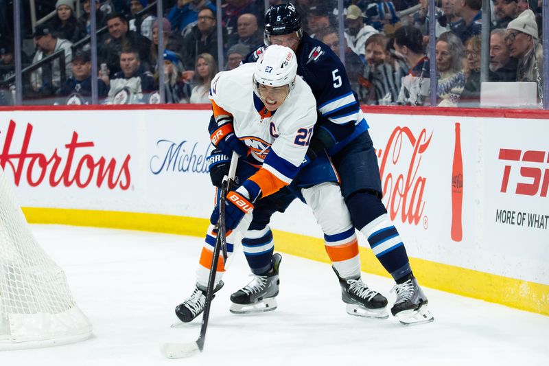 Jan 16, 2024; Winnipeg, Manitoba, CAN; New York Islanders forward Anders Lee (27) tries to skate away from Winnipeg Jets defenseman Brenden Dillon (5) during the first period at Canada Life Centre. Mandatory Credit: Terrence Lee-USA TODAY Sports