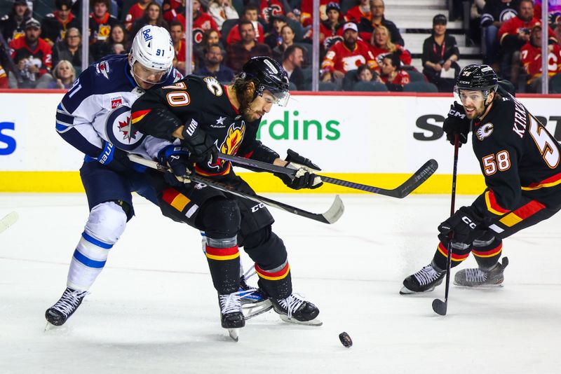 Oct 26, 2024; Calgary, Alberta, CAN; Calgary Flames left wing Ryan Lomberg (70) and Winnipeg Jets center Cole Perfetti (91) battles for the puck during the first period at Scotiabank Saddledome. Mandatory Credit: Sergei Belski-Imagn Images