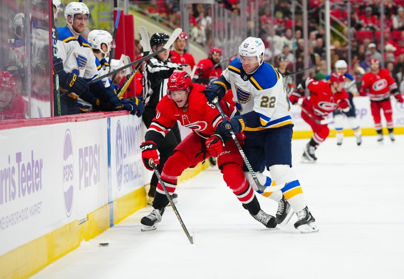 Nov 17, 2024; Raleigh, North Carolina, USA;  St. Louis Blues defenseman Ryan Suter (22) checks Carolina Hurricanes left wing Eric Robinson (50) during the first period at Lenovo Center. Mandatory Credit: James Guillory-Imagn Images