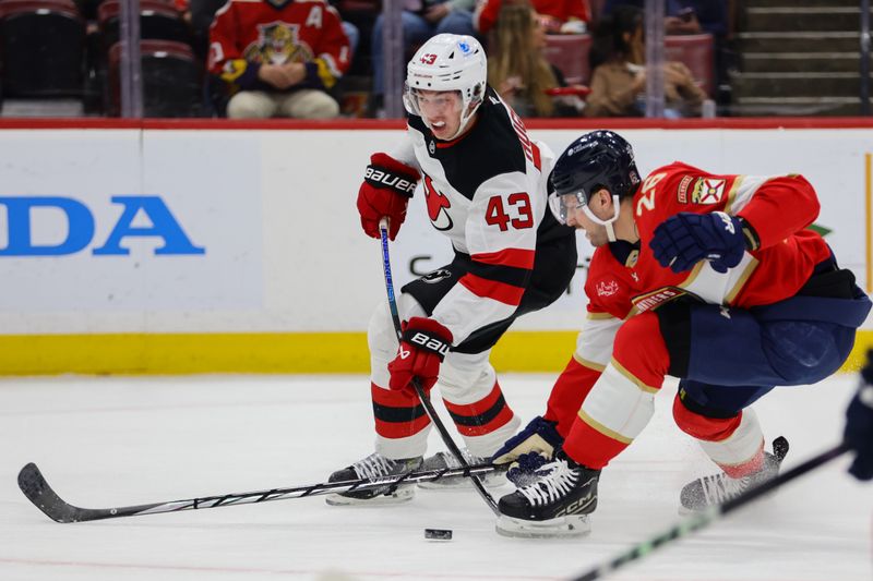 Nov 14, 2024; Sunrise, Florida, USA; New Jersey Devils defenseman Luke Hughes (43) moves the puck against Florida Panthers defenseman Uvis Balinskis (26) during the first period at Amerant Bank Arena. Mandatory Credit: Sam Navarro-Imagn Images