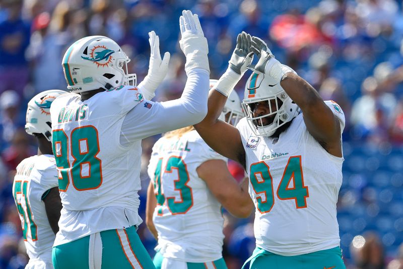 Miami Dolphins defensive tackle Christian Wilkins (94) greets defensive tackle Raekwon Davis (98) before an NFL football game against the Buffalo Bills in Orchard Park, N.Y., Sunday, Oct. 1, 2023. (AP Photo/Adrian Kraus)