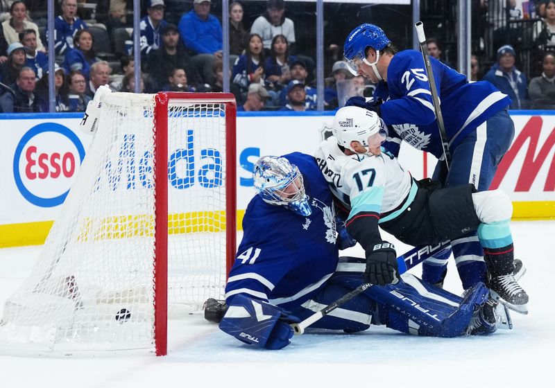 Oct 18, 2025; Toronto, Ontario, CAN; Toronto Maple Leafs defenseman Brandon Carlo (25) battles with Seattle Kraken left wing Jaden Schwartz (17) as the puck goes past  goaltender Anthony Stolarz (41) for a goal during the second period at Scotiabank Arena. Mandatory Credit: Nick Turchiaro-Imagn Images