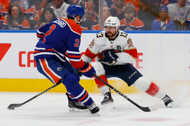Jun 4, 2025; Edmonton, Alberta, CAN; Edmonton Oilers defenseman Evan Bouchard (2) and Florida Panthers center Sam Reinhart (13) attempt to get a loose puck in the second period in game one of the 2025 Stanley Cup Final at Rogers Place. Mandatory Credit: Perry Nelson-Imagn Images