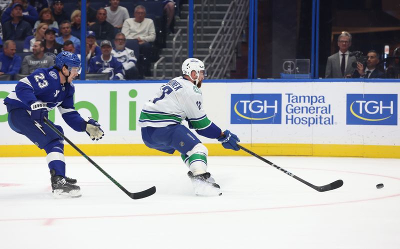 Oct 15, 2024; Tampa, Florida, USA; Vancouver Canucks defenseman Filip Hronek (17) and Tampa Bay Lightning center Michael Eyssimont (23) skate after the puck during the third period at Amalie Arena. Mandatory Credit: Kim Klement Neitzel-Imagn Images