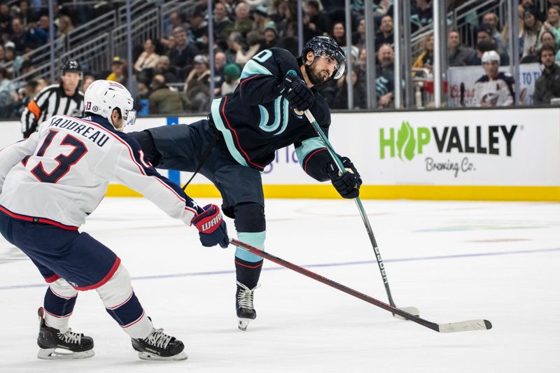 Jan 28, 2024; Seattle, Washington, USA; Seattle Kraken forward Matty Beniers (10) takes a shot Columbus Blue Jackets forward Johnny Gaudreau (13) during the second period at Climate Pledge Arena. Mandatory Credit: Stephen Brashear-USA TODAY Sports