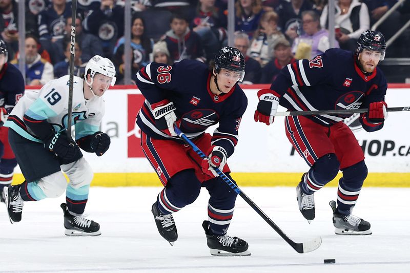 Jan 16, 2025; Winnipeg, Manitoba, CAN; Winnipeg Jets center Morgan Barron (36) skates up the ice with Winnipeg Jets center Adam Lowry (17) chased by Seattle Kraken left wing Jared McCann (19) in the second period at Canada Life Centre. Mandatory Credit: James Carey Lauder-Imagn Images