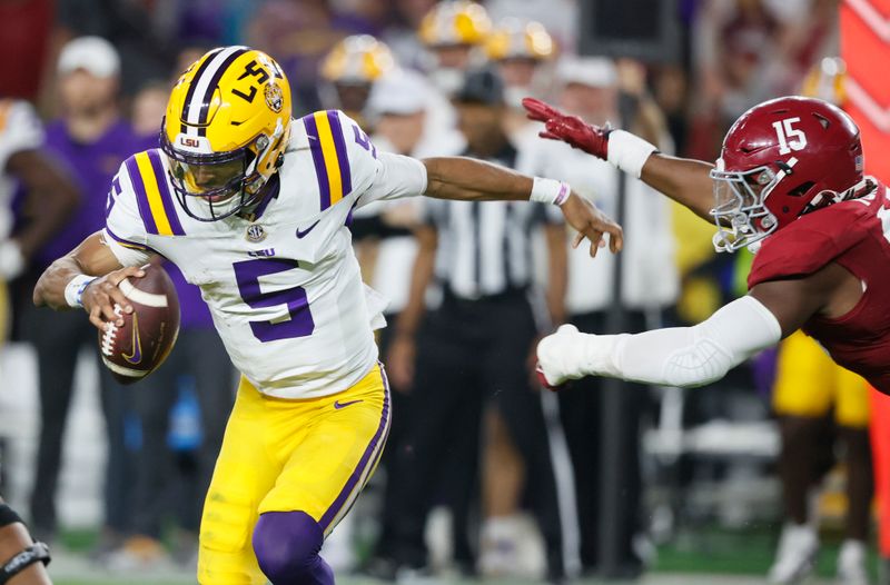 Nov 4, 2023; Tuscaloosa, Alabama, USA; LSU Tigers quarterback Jayden Daniels (5) escapes from the pressure of Alabama Crimson Tide linebacker Dallas Turner (15) during the first half at Bryant-Denny Stadium. Mandatory Credit: Butch Dill-USA TODAY Sports