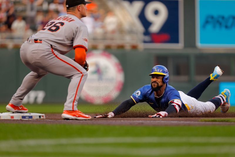 May 9, 2025; Minneapolis, Minnesota, USA; Minnesota Twins center fielder Byron Buxton (25) slides into third base for a triple as San Francisco Giants third baseman Matt Chapman (26) awaits the throw in the first inning at Target Field. Mandatory Credit: Bruce Kluckhohn-Imagn Images